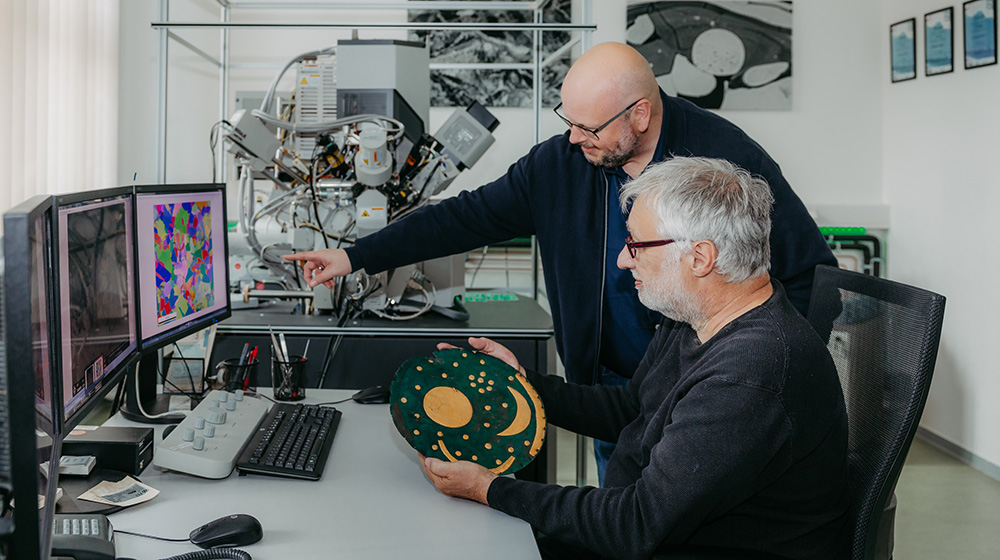 /unimagdeburg_media/Presse/Bilder/Pressemitteilungen/2025/Christian_Heinrich+Wunderlich+mit+einer+Replik+der+Himmelsscheibe+von+Nebra+und+Prof_+Dr_+Thorsten+Halle+im+Labor+auf+dem+Campus+der+Universit%C3%A4t_+in+dem+die+Untersuchungen+stattfanden_+%28c%29+Jana+D%C3%BCnnhaupt+Uni+Magdeburg-height-560-width-1000-p-120153.jpg